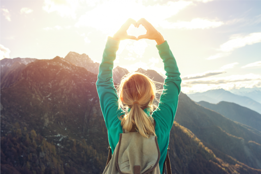 Girl hand heart shape peak of mountain