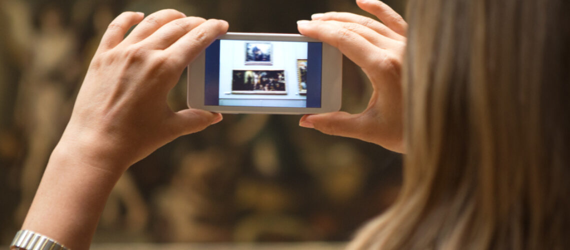 Frau fotografiert mit Smartphone Bild im Museum ab