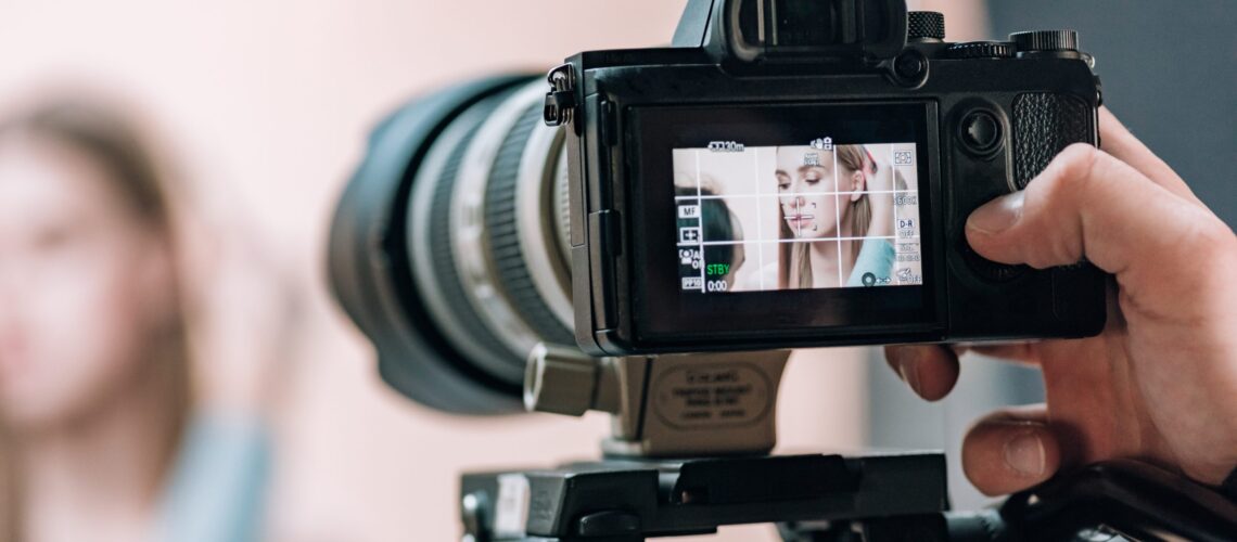 Selective focus of beautiful model on camera display in photo studio